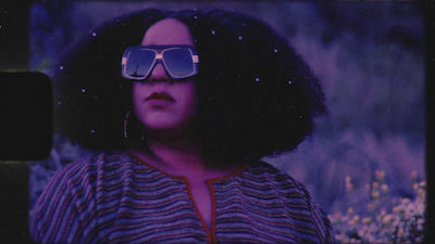 Musician Brittany Howard against a purple background, wearing shades